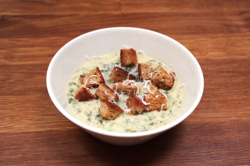 Lautasellinen lehtikaalikeittoa, jonka pinnalla leipäkuutioita ja parmesan-juustoa.