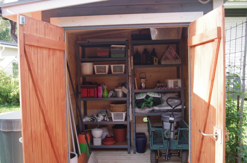 Puutarhavaja sisäpuolelta. Tavarat järjestyksessä hyllyillä.