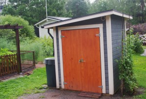 Pieni siniharmaa puutarhavaja, jossa oranssi ovi