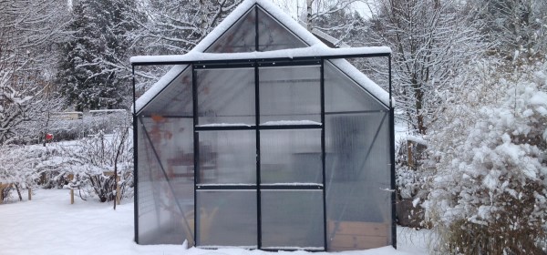 Talvinen kasvihuone lumisella pihalla