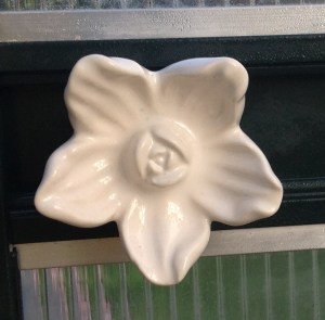 Valkoisen kukan mallinen posliininuppi ovenkahvana kasvihuoneessa