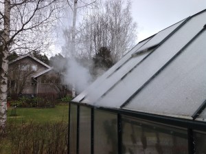 Kasvihuoneen lasien raoista puskee ulos höyryä pesussa.