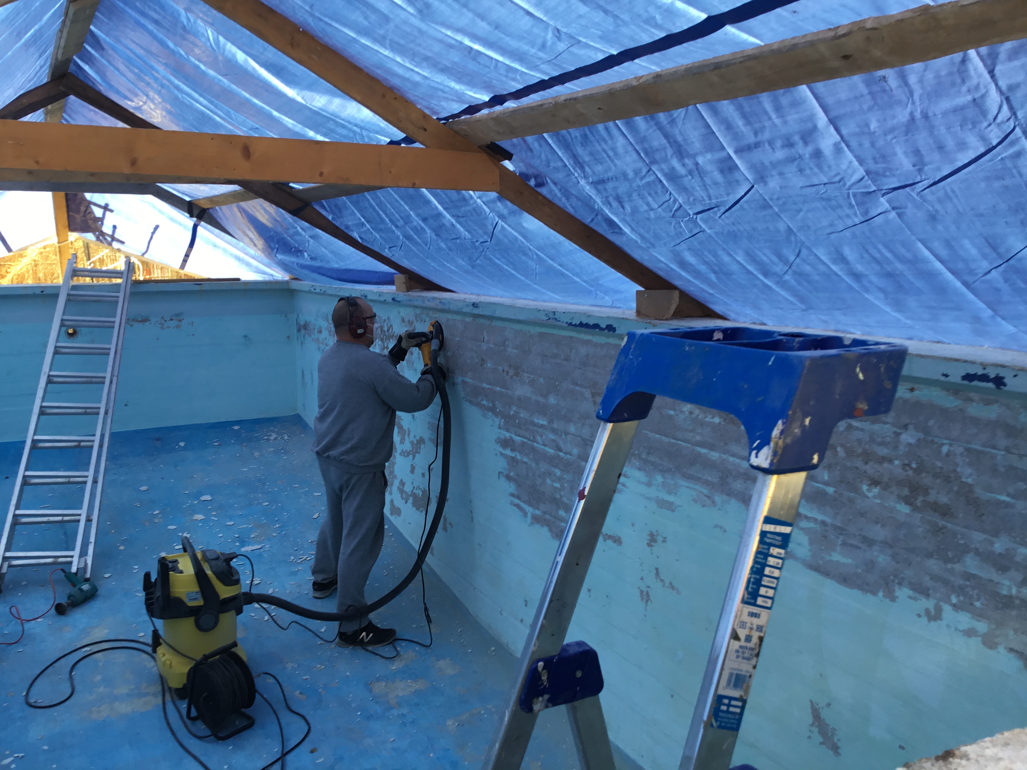 Mies hioo vanhaa maalia tyhjässä uima-altaassa.