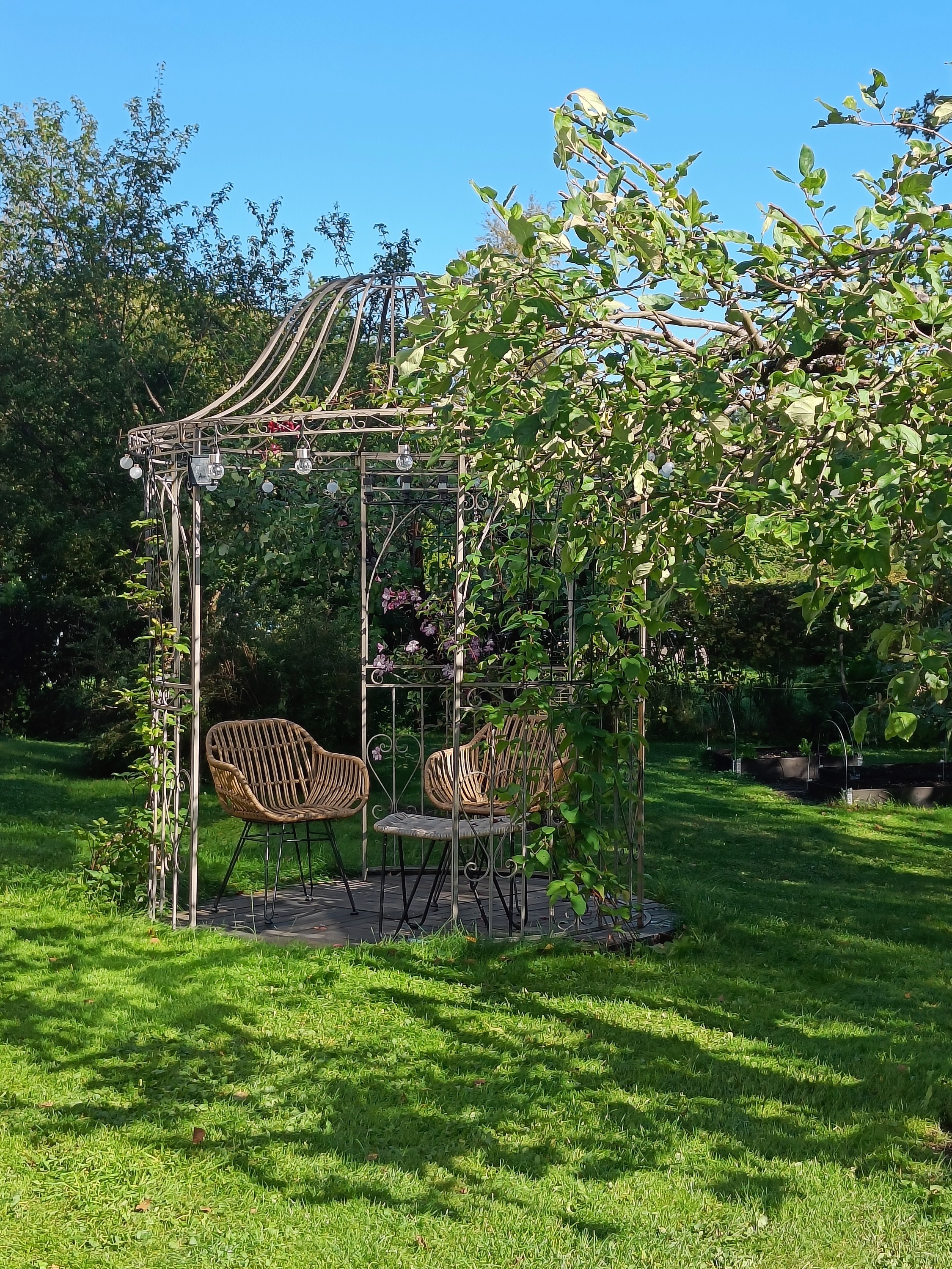 Metallinen paviljonki omakotitalon puutarhassa.