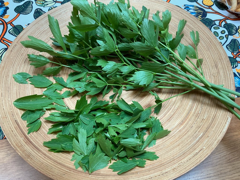 Tuoreita lipstikan oksia ja lehtiä vadilla.